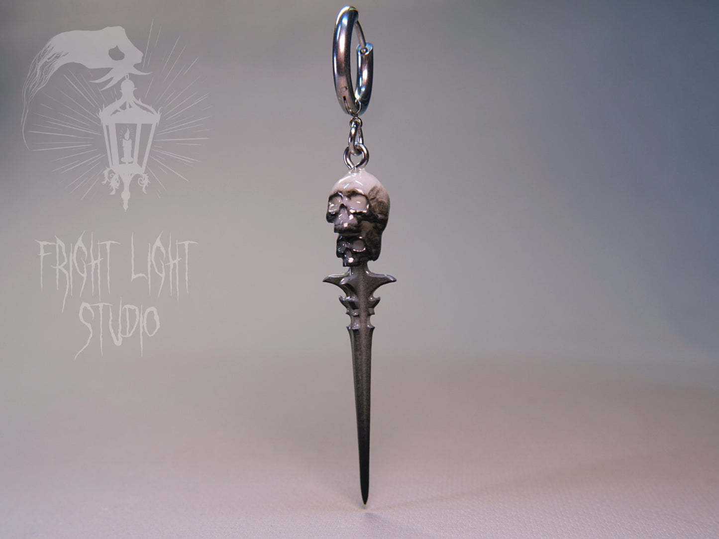 Gothic skull dagger charm on a thin silver hoop.