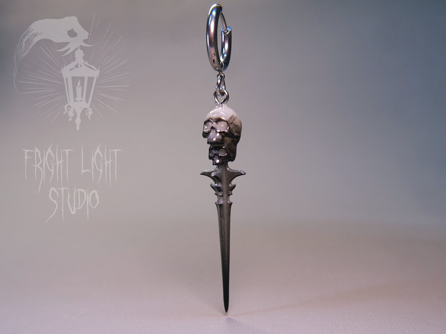 Gothic skull dagger charm on a thin silver hoop.