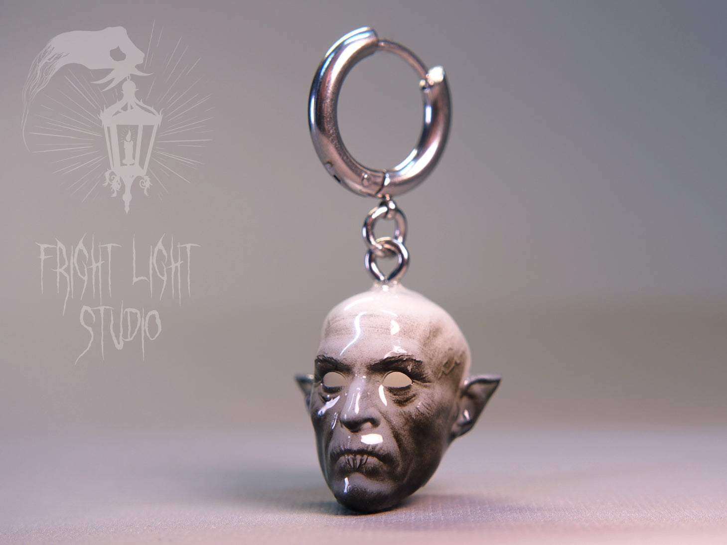 Nosferatu vampire charm on a thin silver hoop earring.